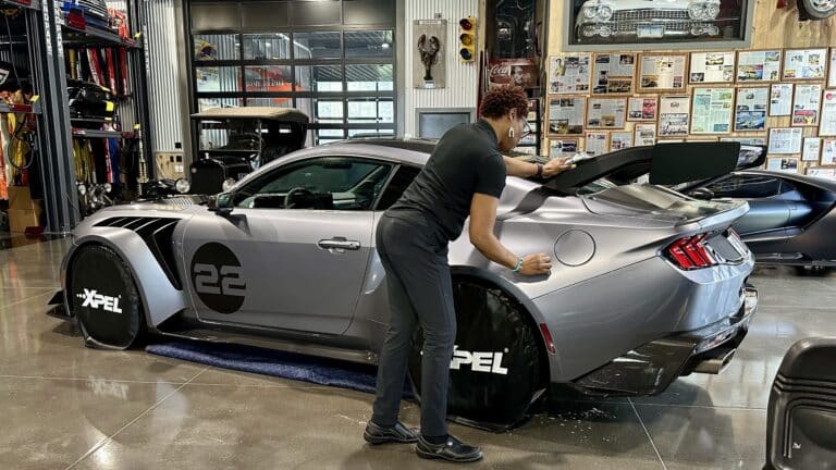 Installer applying XPEL Stealth satin paint protection film to a Ford Mustang GTD, installed on-site by Exclusive Paint Protection