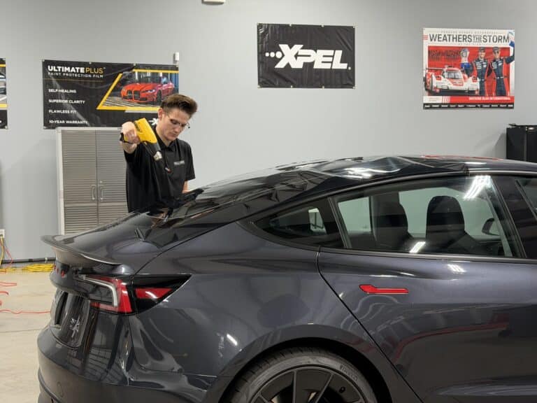 EPP installer heat-shrinking XPEL tint film to the rear glass of a Tesla Model 3 in the studio