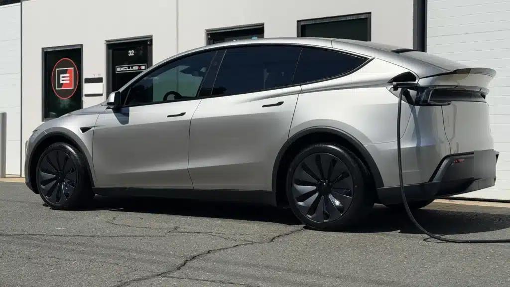Silver Tesla Model Y L with XPEL PRIME ceramic window tint, charging outside Exclusive Paint Protection's Charlotte studio, Suite 32 on Chastain Ave
