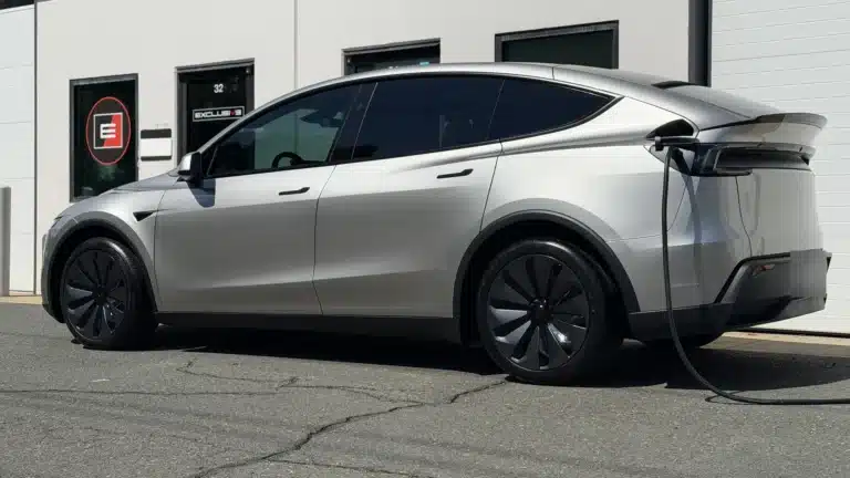 Silver Tesla Model Y L with XPEL PRIME ceramic window tint, charging outside Exclusive Paint Protection's Charlotte studio, Suite 32 on Chastain Ave