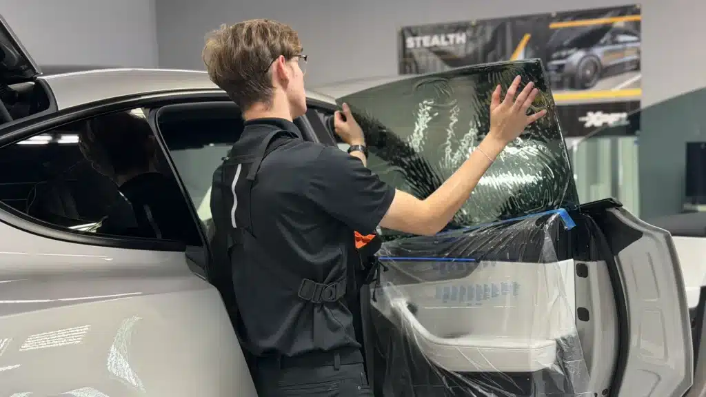 EPP installer fitting XPEL PRIME ceramic window tint to the rear door glass of a Tesla Model Y L at Exclusive Paint Protection's Charlotte studio