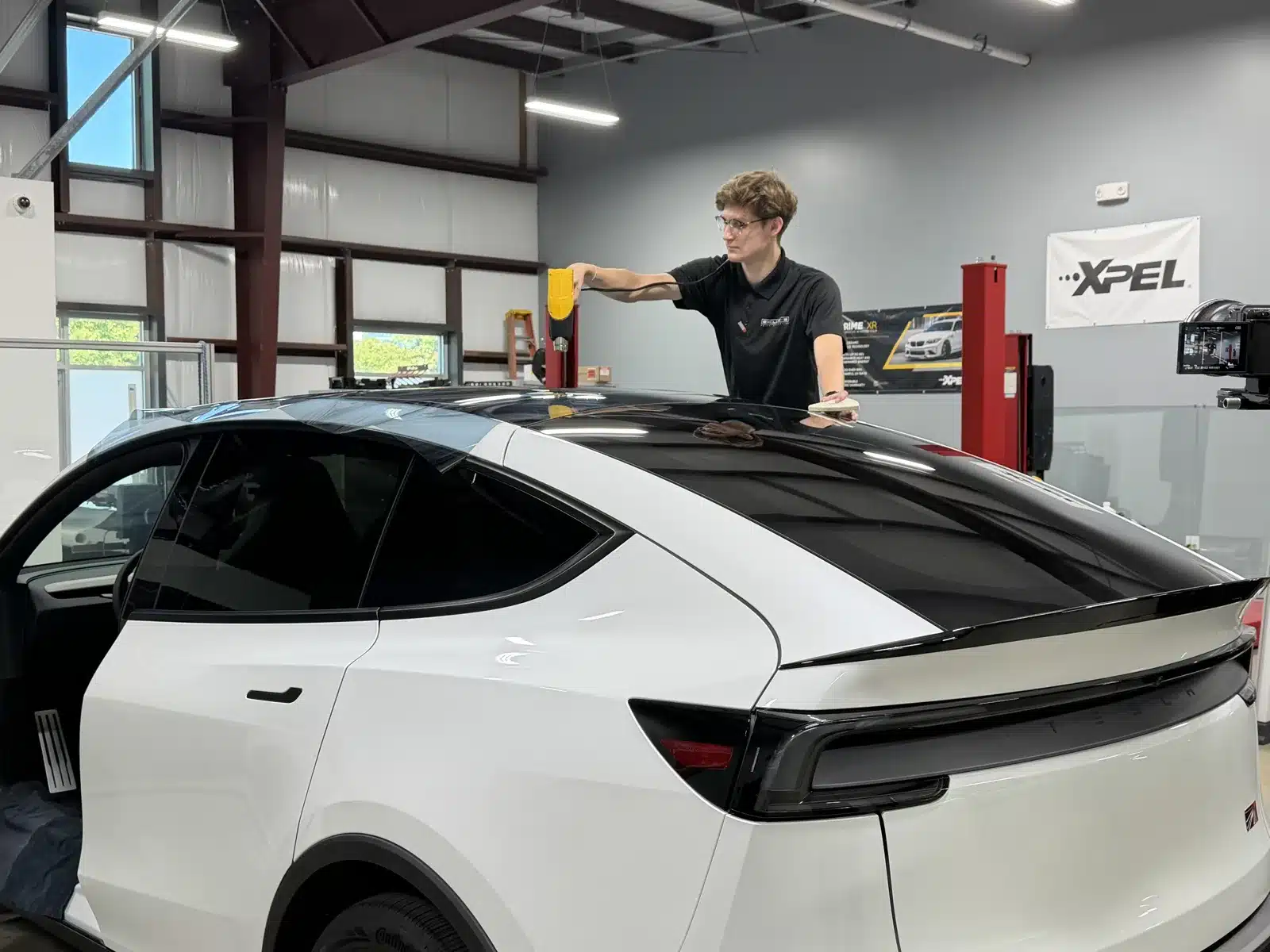 EPP installer heat-forming XPEL PRIME XR PLUS ceramic window tint on the rear glass of a white Tesla Model Y L at Exclusive Paint Protection's Huntersville studio